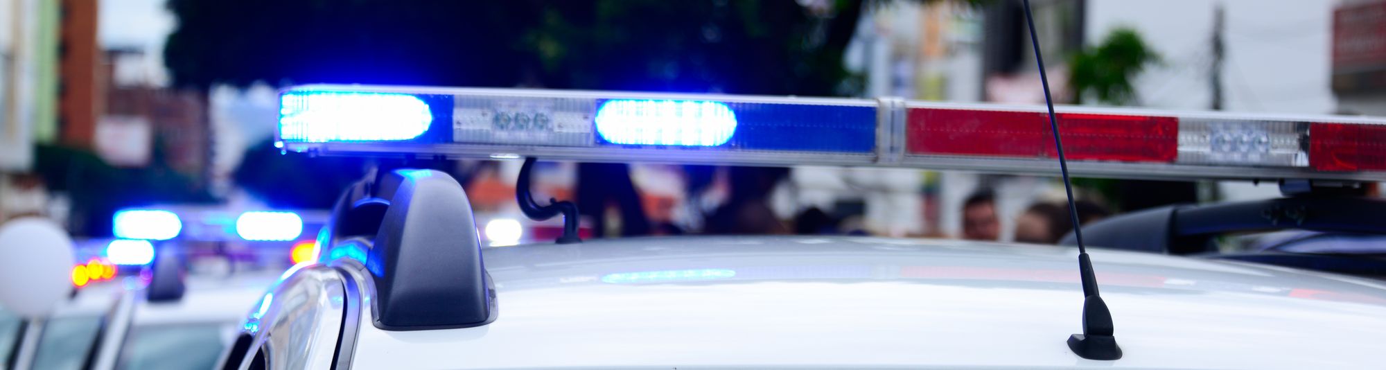 Blue and red emergency light bar on a patrol vehicle, with other vehicles behind